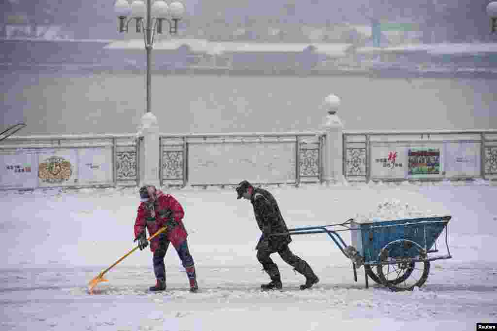 Dua orang pekerja jalanan di kota Jilin, provinsi Jilin China yang dilanda hujan salju. 