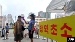 지난 8월 북한 평양역 입구에서 역무원이 신종 코로나바이러스 방역을 위해 승객들의 체온을 재고 있다.