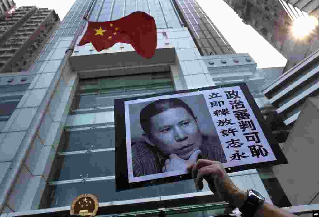 A placard with a photo of legal scholar Xu Zhiyong is raised by a demonstrator protesting against a Chinese court’s decision to sentence him to prison, outside the Chinese liaison office in Hong Kong. Xu was sentenced Sunday to four years in prison on the charge of disturbing order in public places.