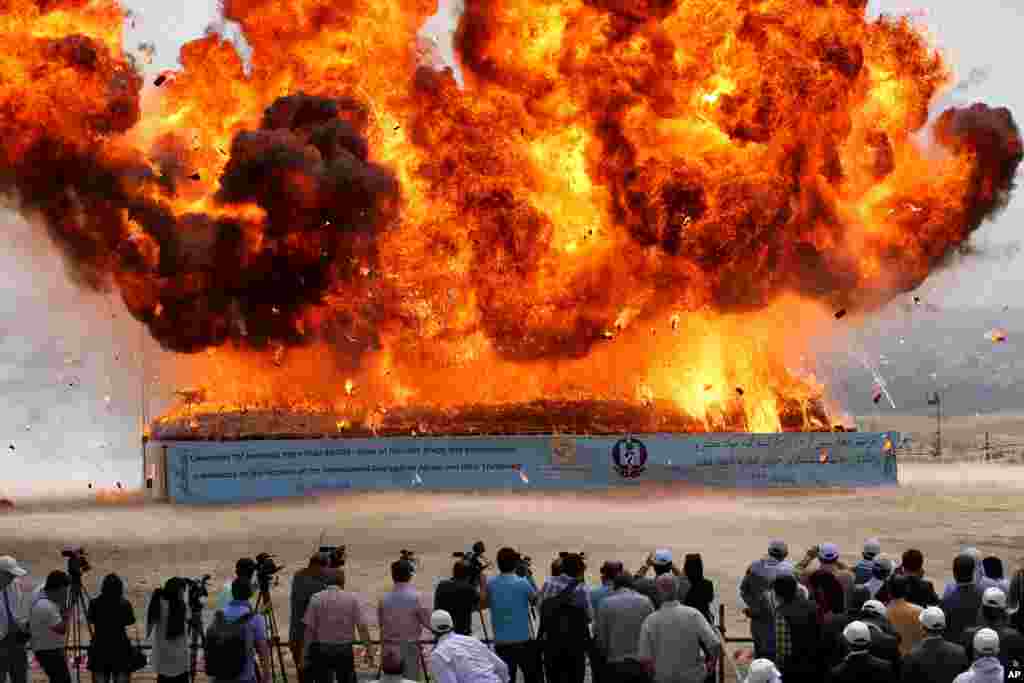 People watch as a pile of seized narcotics is set ablaze during a ceremony commemorating International Day Against Drug Abuse and Illicit Trafficking in Tehran, Iran.