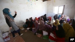 FILE - Afghan internally displaced school girls and women study at a class near their temporary homes on the outskirts of Kabul, Afghanistan, Oct. 30, 2017. 