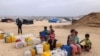Displaced Palestinian children wait by containers for water supply at their tent camp in Rafah in the southern Gaza Strip on April 26, 2024 amid the ongoing conflict between Israel and the Palestinian militant group Hamas. (Photo by MOHAMMED ABED / AFP)