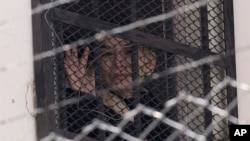 La expresidenta interina de Bolivia, Jeanine Áñez, saluda desde una ventana de la cárcel de mujeres de Miraflores a sus partidarios que protestan por su liberación en La Paz, Bolivia, el miércoles 18 de agosto de 2021.