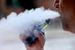 FILE - A man exhales while smoking an e-cigarette in Portland, Maine, Aug. 28, 2019.