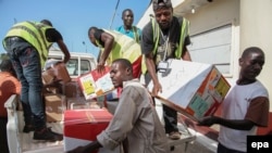 Des travailleurs déchargent un avion à l'aéroport Spriggs Payne à Monrovia, au Libéria, 2 avril 2014. epa/ AHMED JALLANZO