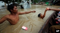 Seorang anak laki-laki menerima bantuan makanan di dekat wilayah permukiman di Nyaung Tone, di delta Sungai Irrawaddy, sebelah barat daya Yangon, Myanmar (7/8).