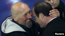 Le président français François Hollande (gauche) et l'ex-otage Serge Lazarevic s'étreignent après avoir prononcé des discours à l'aéroport militaire de Villacoublay, près de Paris, le 10 décembre 2014.