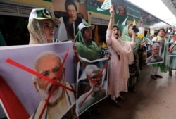 Women hold crossed out portrait of Indian Prime Minister Narendra Modi as they participate in a train march to mark the first anniversary of India's decision to revoke the disputed region's semi-autonomy, in Karachi, Pakistan, Aug. 5, 2020.