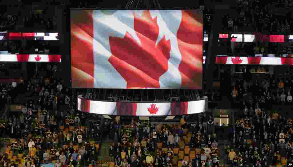 Fans stand up for the Canadian national anthem prior to an NHL hockey game between the Boston Bruins and New York Islanders in Boston. The tribute was for Cpl. Nathan Cirillo, 24, who was killed by a gunman who shot him at Canada's National War Memorial in Ottawa, Oct. 23, 2014.