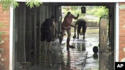 Local residents clear away the mud from their flooded home in Brisbane, Australia. Parts of Brisbane reopened as deadly floodwaters that had swamped entire neighborhoods recede, revealing streets and thousands of homes covered in a thick layer of putrid