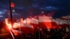 FILE - Demonstrators burn flares and wave Polish flags during an annual march to mark Poland's National Independence Day, in Warsaw, Poland, Nov. 11, 2017. 