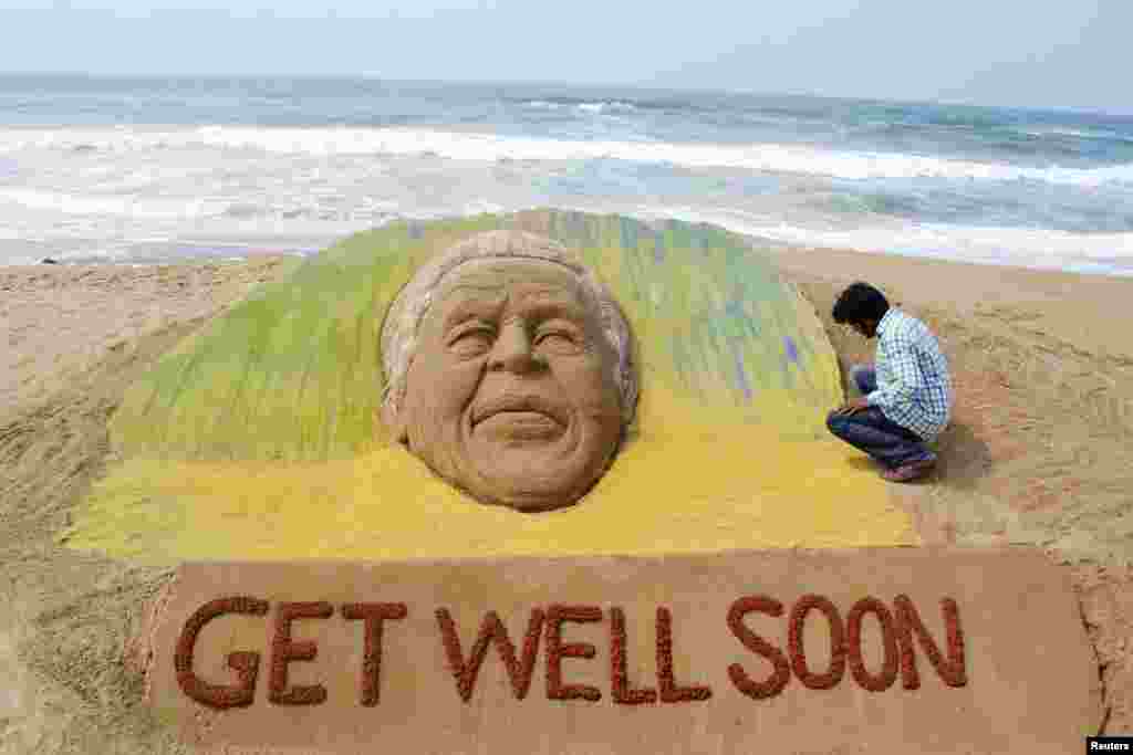 Seniman Sudarshan Pattnaik menciptakan bentuk wajah menyerupai mantan Presiden Afrika Selatan, Nelson Mandela dari pasir di pantai di Puri, India, 9 Juni 2013.