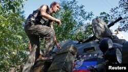 A pro-Russian separatist climbs atop an armored personnel carrier as he guards a position in the eastern Ukrainian town of Ilovaysk Aug. 31, 2014.