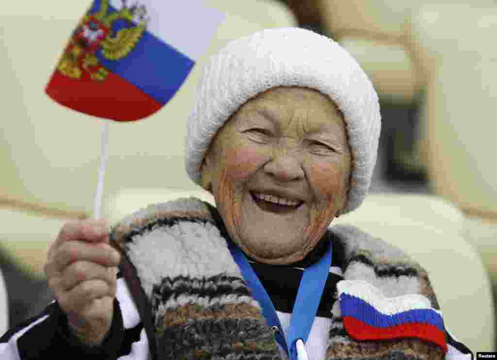 A Russian supporter waves the national flag before the women's 5,000-meter speed skating race at the Adler Arena, Sochi, Feb. 19, 2014.
