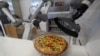 Robot pizzaiolo menyiapkan pizza di depan mata pelanggan di ruang pamer startup makanan Prancis, sebagai ilustrasi. (Foto: Reuters)