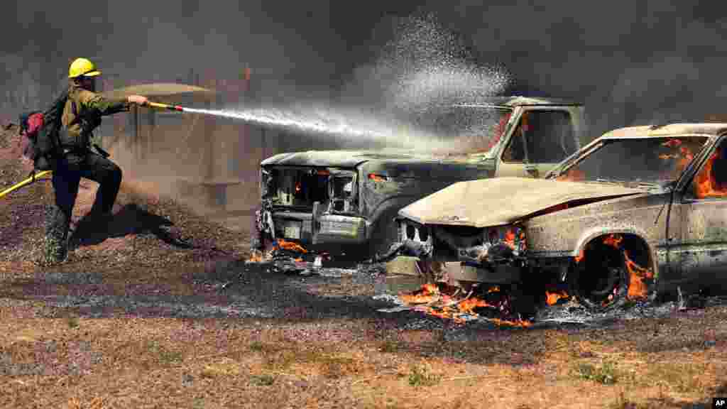 Un pompier essaye d'éteindre l'incendie sur des voitures en feu à Lower Lake, en Californie, le 14 août 2016.