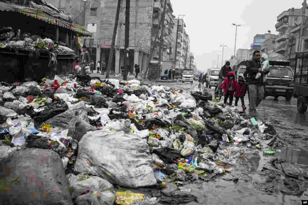 A family crosses a street piled with garbage in Aleppo, Syria, January 5, 2013.