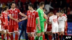 Le défenseur allemand du Bayern Munich Mats Hummels, à gauche, se serre la main avec son coéquipier attaquant Robert Lewandowski à la fin du quart de finale de la Champions League contre le FC Sevilla au stade Ramon Sanchez Pizjuan à Séville, 3 avril 2018