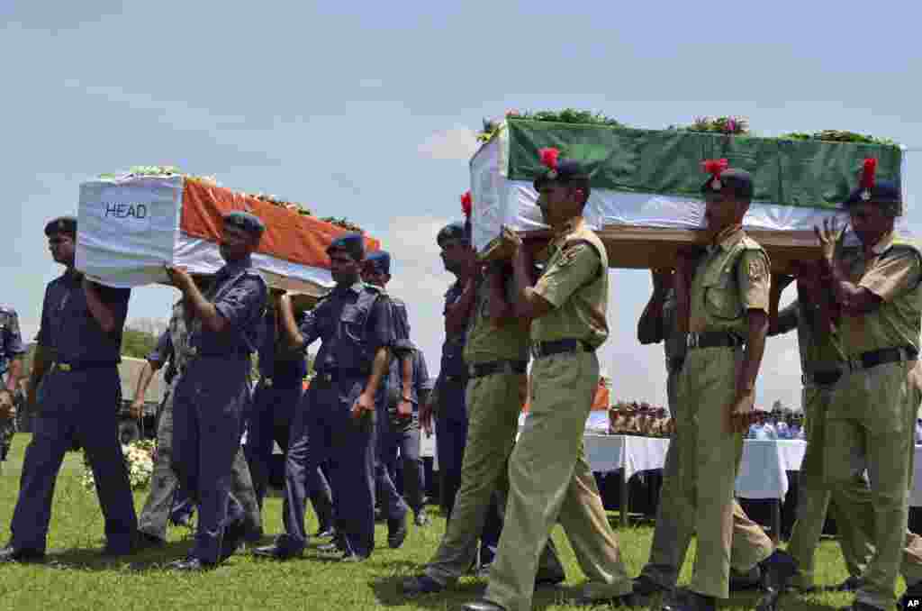 Petugas keamanan India mengusung peti mati yang berisi jasad para korban helikopter yang jatuh dalam misi penyelamatan banjir di Dehradun, India utara. Helikopter angkatan udara itu menghantam sisi gunung dan jatuh ke sungai pada hari Selasa, menewaskan lima anggota kru dan tiga orang warga sipil dalam pesawat itu.
