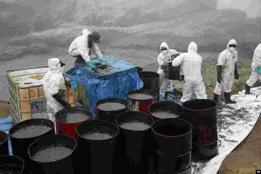Workers remove oil from Cavero Beach in the Ventanilla district of Callao, Peru. The oil spill on the Peruvian coast was caused by the waves from an eruption of an undersea volcano in the South Pacific nation of Tonga.