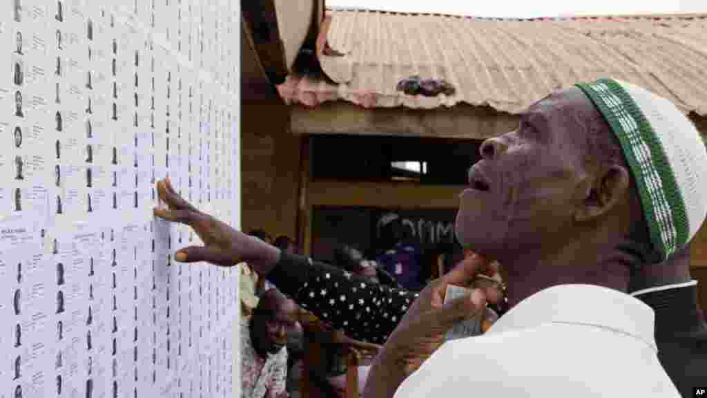 Un homme cherche son nom sur une liste avant de s'enregistrer et de voter en plaçant son bulletin de vote dans l'urne plus tard dans la journée à Lagos, au Nigeria, samedi 28 mars 2015.