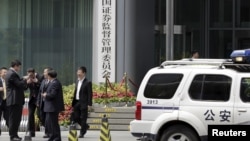 FILE - A police vehicle is seen parked outside a building in Beijing, July 9, 2015.