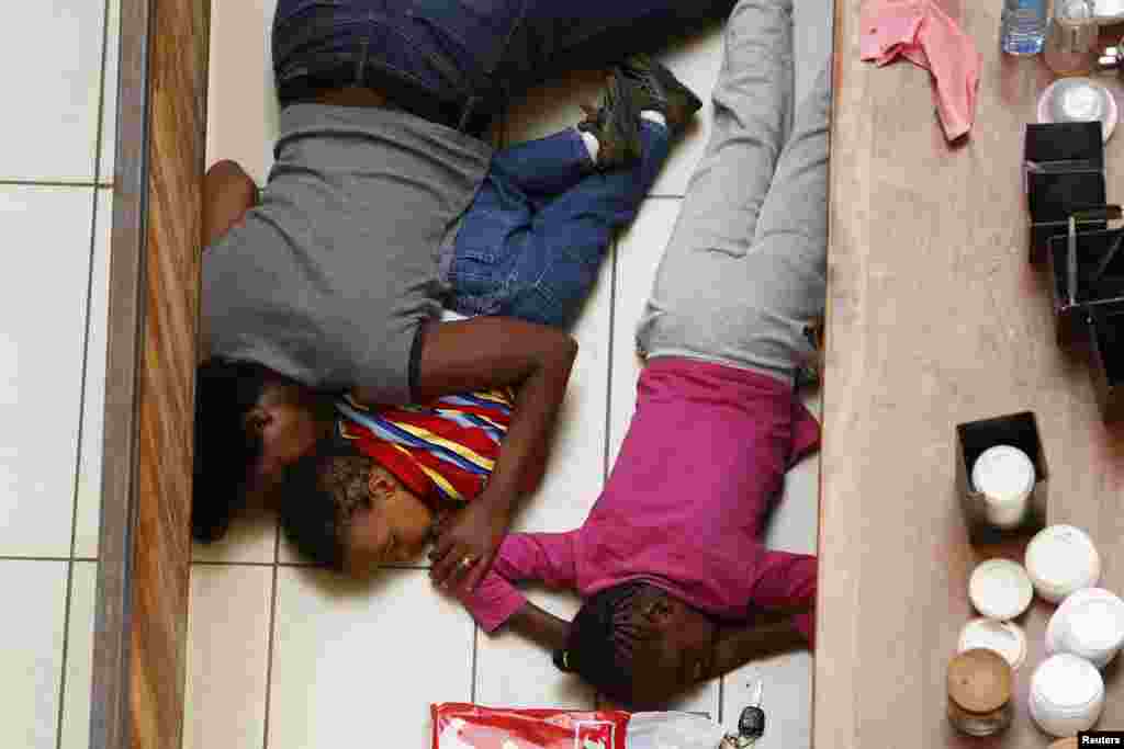 Seorang ibu dan anak-anaknya tiarap bersembunyi dari penembak di pusat perbelanjaan Westgate di Nairobi (21/9). (Reuters/Siegfried Modola)