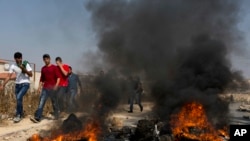 Demonstran Palestina membakar ban dan bentrok dengan tentara Israel setelah tentara Israel menggeledah rumah Omar al-Abed, 20, yang diidentifikasi oleh tentara Israel sebagai pelaku penyerangan di pemukiman Israel, Halamish.