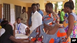 Une femme met son bulletin dans l'urne au bureau de vote de Seme Podji, au Bénin, le 6 mars 2016. (AP Photo/Virgile Ahissou)