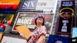 New York'taki Times Meydanı'nda bir turist rehberi elindeki yelpazeyle sıcak havayla mücadele ediyor.