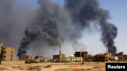 Seorang pria berjalan saat asap mengepul dari atas gedung setelah pemboman udara menyusul bentrokan antara Pasukan Dukungan Cepat paramiliter dan tentara di Khartoum Utara, Sudan, 1 Mei 2023. (Foto: REUTERS/Mohamed Nureldin Abdallah)