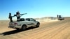 FILE - Forces loyal to Syria's President Bashar al-Assad ride on pickup trucks mounted with weapons in the Badia, in the southeast Syrian desert, in this handout picture provided by SANA, June 13, 2017.