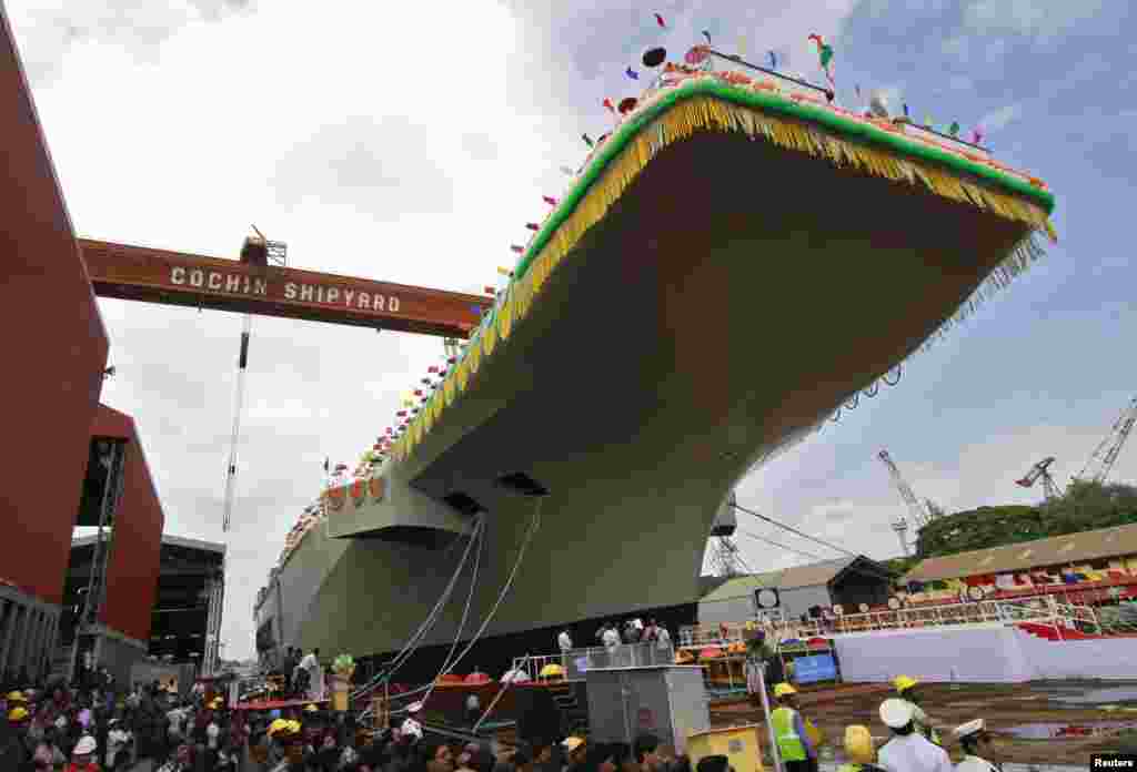 Para karyawan Cochin Shipyard berdiri di dekat Pembawa Pesawat India P-71 'Vikrant' yang dibangun untuk Angkatan Laut India saat peluncuran di kota India selatan Kochi, India.