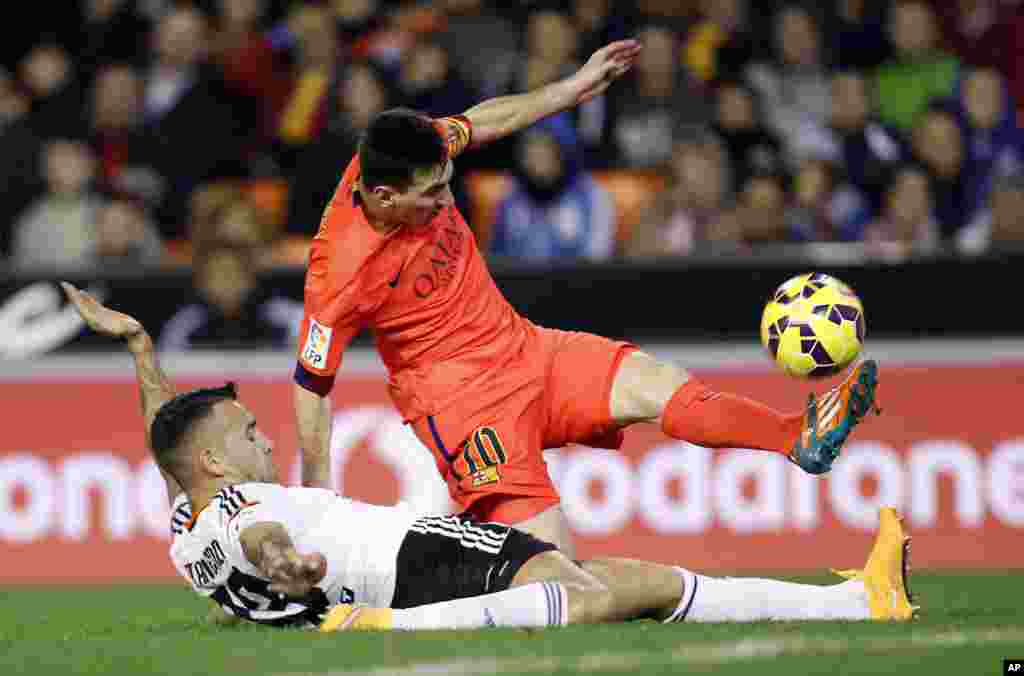 Lionel Messi de Barcelone, de l'Argentine, en haut, engagé dans un duel avec Otamendi de Valence lors d'un match de football de La Liga espagnole au stade Mestalla à Valence, en Espagne, le dimanche 30 novembre 2014.