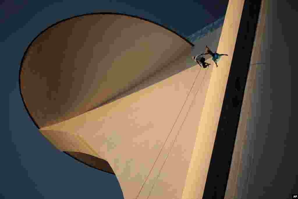 Dancers rappel from the Digital TV Tower as part of an aerial performance in Brasilia, Brazil, Friday, Aug. 31, 2012. The tower, also known as the Flor do Cerrado, was designed by architect Oscar Niemeyer.