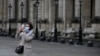 Un turista cubierta con una máscara de sanidad se hace una selfie frente al museo del Louvre el viernes 28 de febrero de 2020 en París. El museo cerró sus puertas el domingo 1 de marzo, por temores al coronavirus.