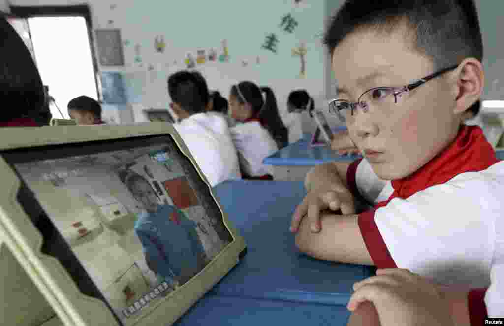 Seorang siswa melihat iPad-nya saat berlangsungnya siaran langsung pelajaran dari astronot di stasiun antariksa Tiangong-1 untuk para pelajar sekolah dasar di Quzhou, provinsi Zhejiang, China (20/6).