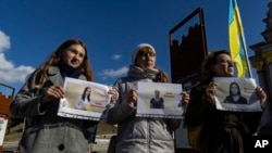 Wanachama wa chama cha waandishi wa habari wa Ukraine wakishikilia picha za waandishi wa habari watatu wanaofungwa na Russia, moja ya picha hizo ni ya Victoria Roshchyna, Oktoba 17.2023. Picha ya AP