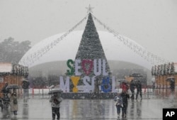FILE - People pass by a Christmas tree in the snow at Gwanghwamun Square in Seoul, South Korea, Tuesday, Jan. 9, 2024. (AP Photo/Ahn Young-joon)