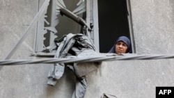 A woman looks out of the window of a building that was damaged during Israeli bombardment at the Al-Daraj neighbourhood in Gaza City on May 21, 2024, amid the ongoing conflict between Israel and the Palestinian militant group Hamas. (Photo by AFP)