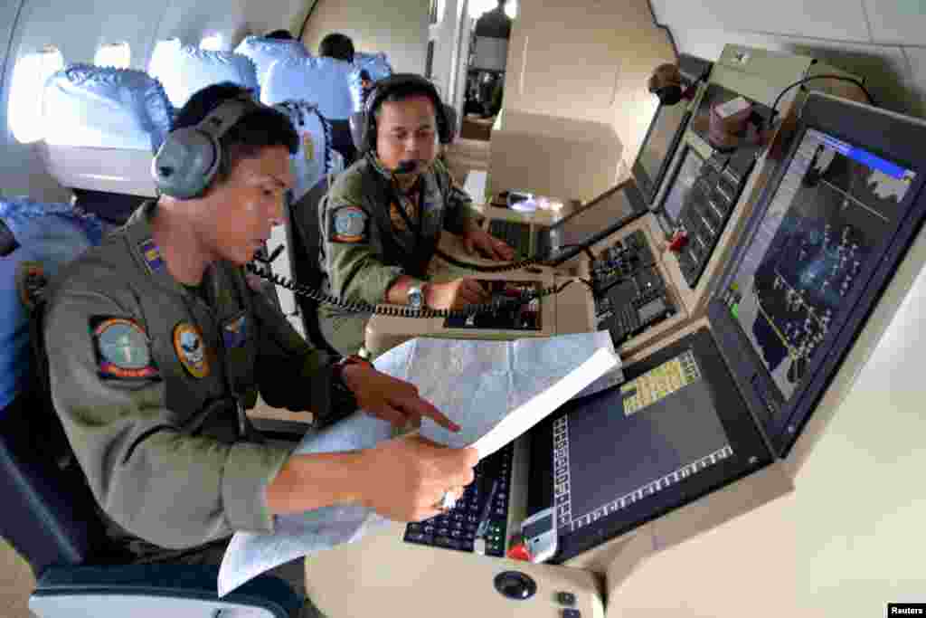 Two members of the Indonesian Navy's Tactical Commanding Operator (TACCO) help with the search for AirAsia flight QZ 8501 on board a CN235 aircraft over Karimun Java, in the Java Sea, Dec. 28, 2014 in this photo taken by Antara Foto.