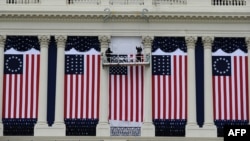 Two workers adjust U.S. flags on the Capitol as preparations continue for the second inauguration of President Barack Obama in Washington, D.C., January 17, 2013.