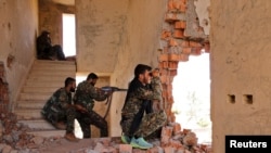 FILE - Kurdish People's Protection Units (YPG) fighters take up positions inside a damaged building in al-Vilat al-Homor neighborhood in Hasaka, Syria, as they monitor the movements of Islamic State fighters, July 22, 2015.