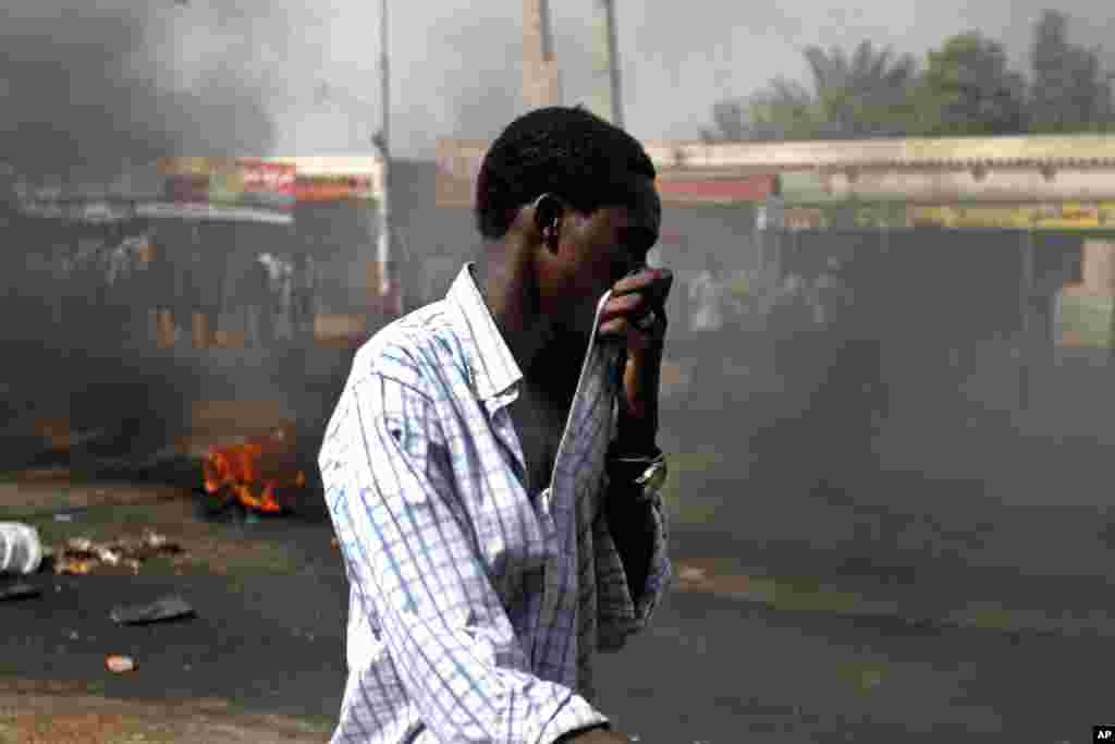A Sudanese man covers his mouth from heavy smoke in Kadro, Sudan, Sept. 25, 2013. 