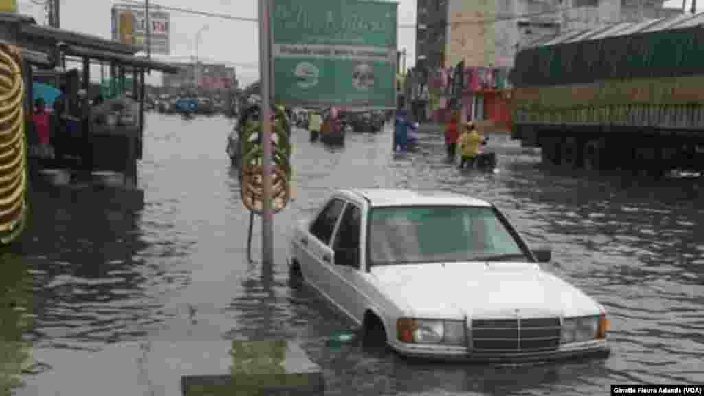 Un homme prend le risque de conduire sans voir les bords de la route inondée dans un quartier avoisinant le stade de l'amitié aujourd'hui baptisé stade Général Mathieu Kerekou, à Cotonou, Bénin, 8 octobre 2016. VOA/Ginette Fleure Adande