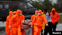 Tim SAR membawa puing-puing AirAsia QZ8501 yang dibawa ke pantai oleh helikopter AL Singapura di pangkalan udara Pangkalan Bun, Kalimantan Tengah, 4 Januari 2015. 