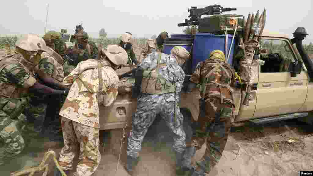 Des soldats tchadiens poussent et tentent de sortir du sable une camionnette de l'armée près de la ligne de front durant la guerre contre le groupe d'insurgés Boko Haram à Gambaru, Nigeria, le 26 février 2015.
