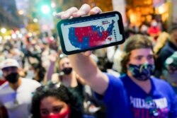FILE - A supporter of President-elect Joe Biden holds up his mobile phone to display the electoral college map outside the Philadelphia Convention Center after the 2020 Presidential Election is called, Nov. 7, 2020.
