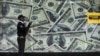FILE - A security guard walks past a montage of old U.S. dollar bills outside a currency exchange bureau in Kenya's capital Nairobi, July 23, 2015. WorldRemit, a British-based money transfer company, recently launched a new digital service in four East African countries.
