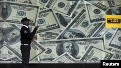 FILE - A security guard walks past a montage of old U.S. dollar bills outside a currency exchange bureau in Kenya's capital Nairobi, July 23, 2015. WorldRemit, a British-based money transfer company, recently launched a new digital service in four East African countries.